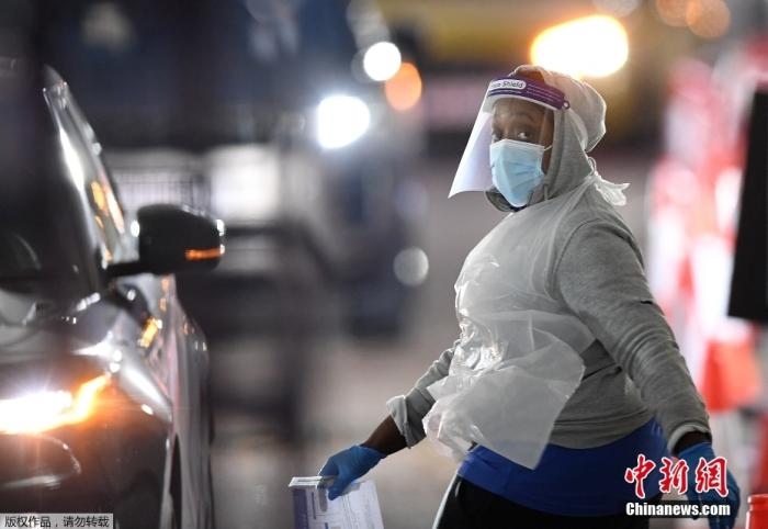 當(dāng)?shù)貢r間12月18日，英國政府公布的數(shù)據(jù)顯示，當(dāng)天英國新增奧密克戎毒株感染病例10059例。鑒于奧密克戎毒株感染病例激增，住院人數(shù)不斷上升，倫敦市長宣布倫敦進入“重大事故”狀態(tài)。圖為倫敦的一個免下車檢測中心，一名醫(yī)務(wù)工作者正準(zhǔn)備對司機進行核酸檢測。