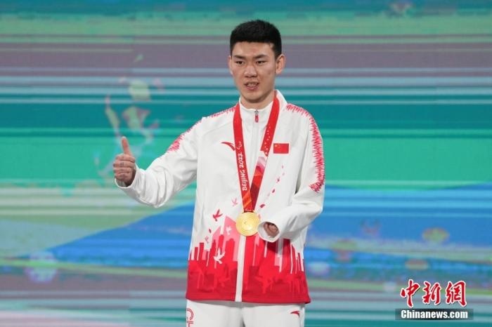 3月6日，梁景怡在延慶頒獎廣場領獎臺上豎起大拇指。當日，在國家高山滑雪中心舉行的北京2022年冬殘奧會殘奧高山滑雪男子超級大回轉—站姿決賽中，中國選手梁景怡奪得冠軍。 <a target='_blank' href='/'>中新社</a>記者 楊華峰 攝