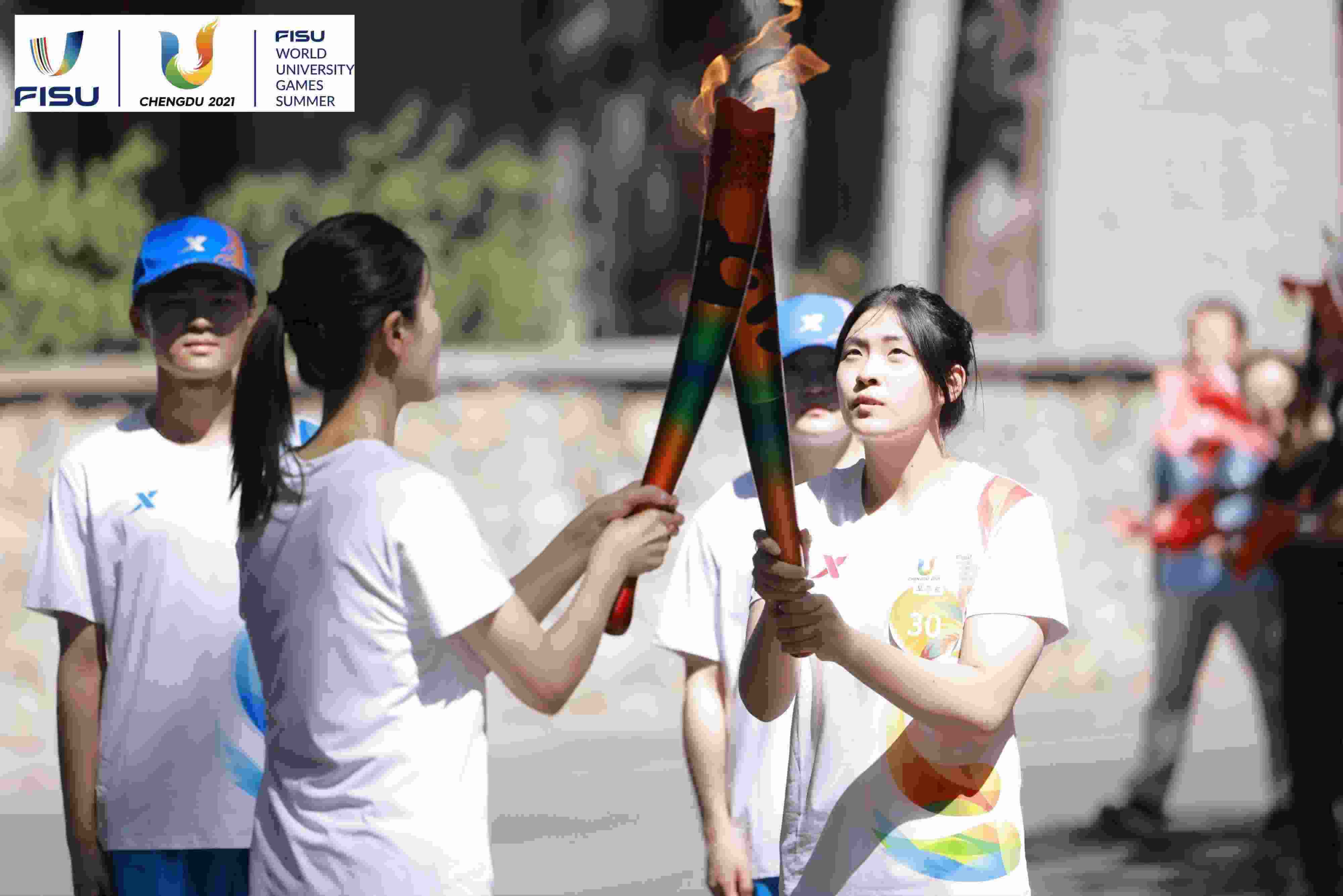 兩名大運會火炬手進行火炬?zhèn)鬟f。 圖片來源：成都大運會執(zhí)委會供圖