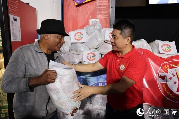 巴西中國浙江商會會長鄭俠茂向社區(qū)居民轉(zhuǎn)交捐贈物資。人民網(wǎng)記者 時元皓攝