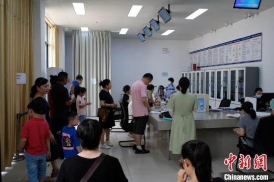 圖為在戶籍辦證廳內(nèi)排隊(duì)等待的家長(zhǎng)和孩子。劉俊聰 攝