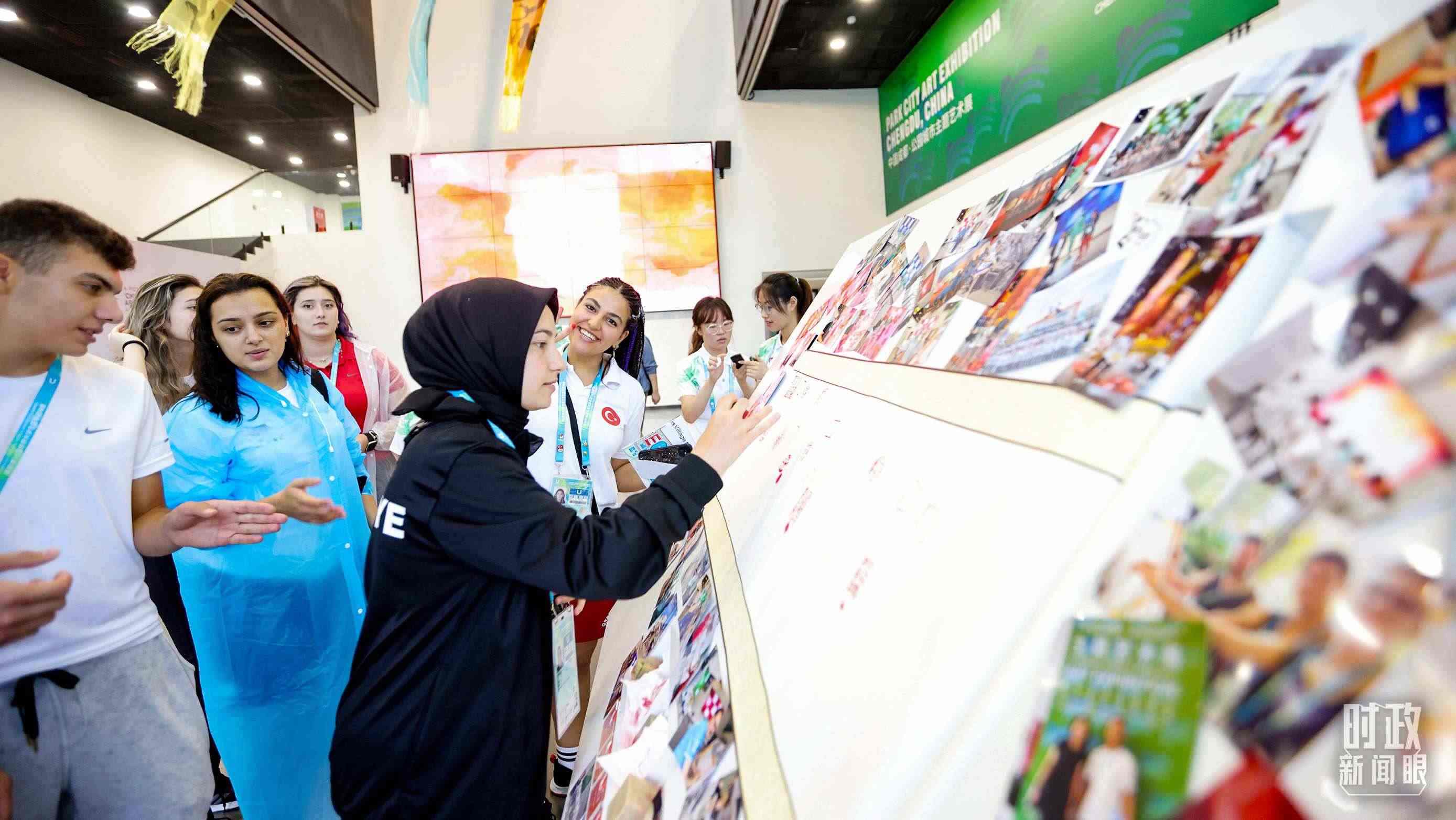 各國(guó)青年運(yùn)動(dòng)員正在參觀成都大運(yùn)村內(nèi)的“雪山下的公園城市，煙火里的幸福成都”主題藝術(shù)展。（總臺(tái)央視記者魏幫軍拍攝）