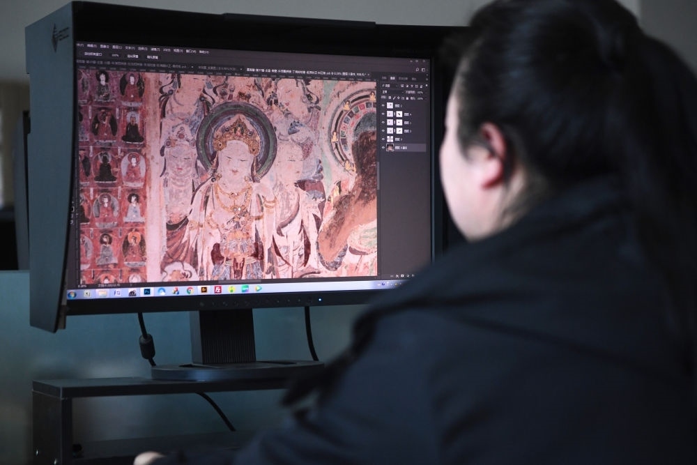 敦煌研究院文物數(shù)字化保護團隊圖像處理人員年海麗在拼接壁畫圖像（2023年4月25日攝）。數(shù)字化探索為莫高窟的保護與傳承開辟了全新路徑，數(shù)字技術讓敦煌文物走出洞窟，跨出國門，走向“永久保存、永續(xù)利用”。新華社記者 陳斌 攝