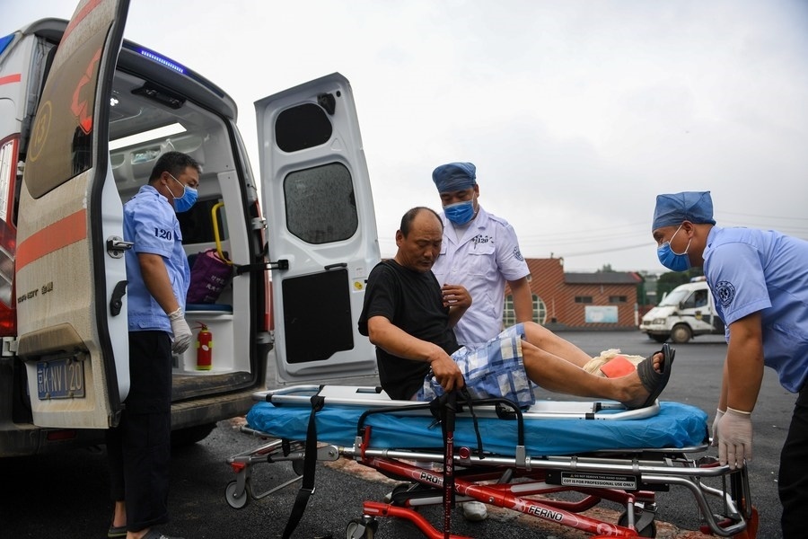 8月1日，在北京市門頭溝區(qū)妙峰山鎮(zhèn)妙峰山民族學(xué)校臨時安置點(diǎn)，北京急救中心工作人員在轉(zhuǎn)運(yùn)一名受傷村民。新華社記者 鞠煥宗 攝