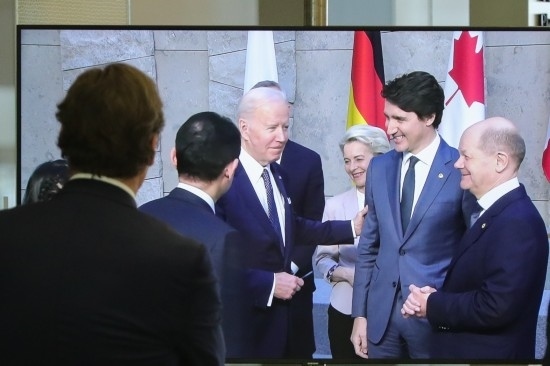 2022年3月24日，在比利時(shí)布魯塞爾的北約總部，一名男子觀看屏幕上美國總統(tǒng)拜登（右四）、歐盟委員會主席馮德萊恩（右三）、加拿大總理特魯多（右二）、德國總理朔爾茨（右一）出席七國集團(tuán)峰會合影儀式的畫面。新華社記者鄭煥松攝