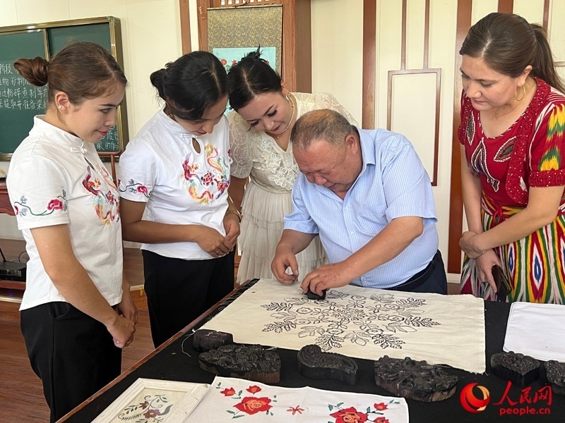 國家級(jí)非物質(zhì)文化遺產(chǎn)模戳印花布技藝傳承人吾吉阿西木?吾舒爾展示模戳印花布的制作過程。人民網(wǎng)記者 常雪梅攝