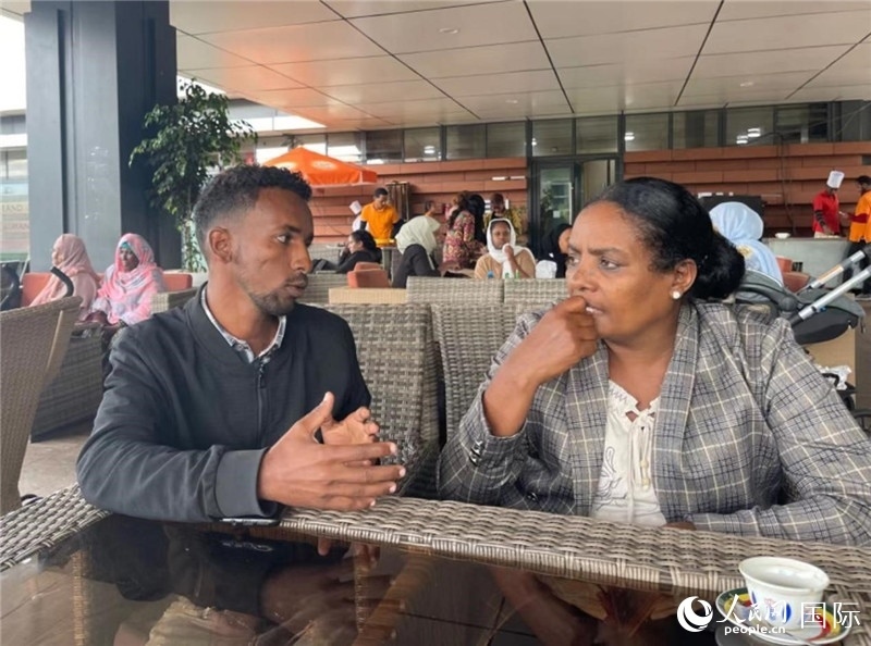 約漢斯（圖左）與德貝拉在友誼廣場咖啡廳交談。人民網(wǎng)記者 趙艷紅攝