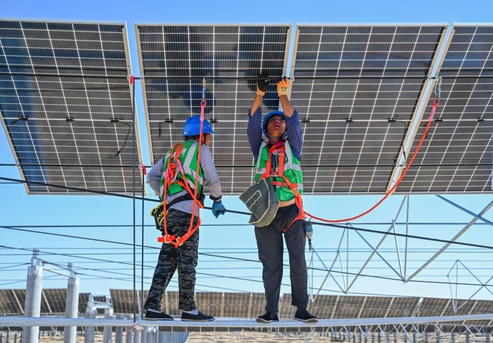 2023年7月22日，工人在位于內(nèi)蒙古杭錦旗庫布其沙漠億利生態(tài)示范區(qū)的蒙西基地庫布其200萬千瓦光伏治沙項(xiàng)目工地安裝光伏板。新華社記者 劉磊 攝