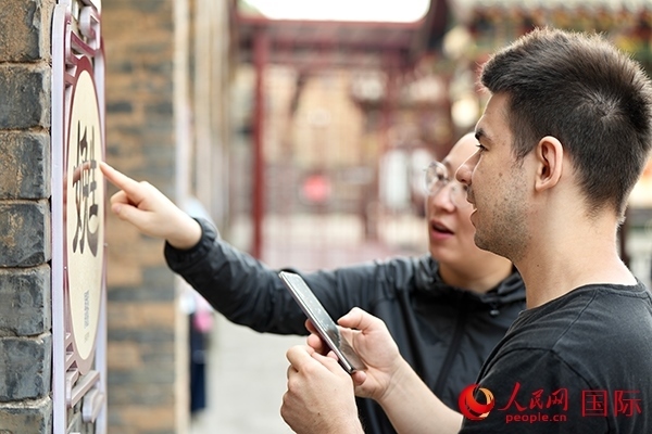 選手安德烈（俄羅斯）在老師指導(dǎo)下學(xué)習(xí)墻壁上張貼的生僻字。人民網(wǎng) 盧鵬宇攝