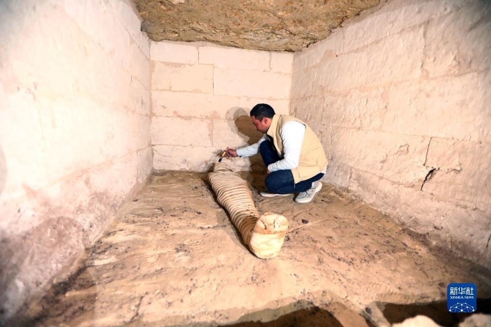 10月15日，在埃及明亞省考古現(xiàn)場，考古人員清理一座石鑿墓中的木乃伊。新華社發(fā)（艾哈邁德·戈馬攝）