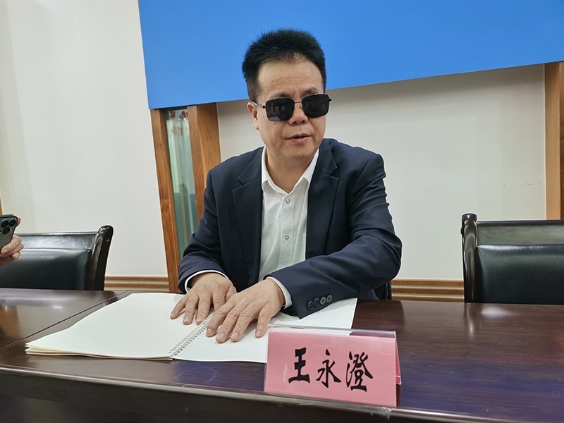 全國人大代表王永澄正在閱讀盲文版代表建議答復(fù)。本報記者 張 璁?dāng)z