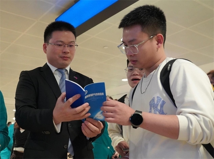 工作人員（左一）在發(fā)放《中國領(lǐng)事保護(hù)與協(xié)助指南》。 中國駐迪拜總領(lǐng)事館供圖