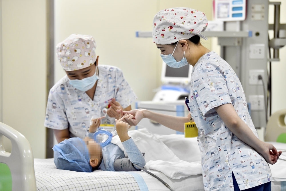 在山東省棗莊市婦幼保健院兒童ICU病房，醫(yī)護人員為完成靶向治療藥物諾西那生鈉的4歲脊髓性肌萎縮癥患兒加油鼓勁（2022年1月1日攝）。諾西那生鈉注射液是我國首個獲批治療脊髓性肌萎縮癥的進口藥物，2019年進入中國市場時，每針價格近70萬元。在2021年國家醫(yī)保目錄藥品談判中，以3.3萬元每針的價格進入新版醫(yī)保藥品目錄。新華社記者 郭緒雷 攝