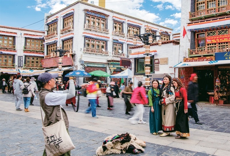 千年八廓街，見證民族團結(jié)。2021年7月，習(xí)近平總書記來到位于西藏拉薩老城區(qū)的八廓街，感慨地說：“千年八廓街，是我們各民族建起來的八廓街。各民族文化在這里交流交往交融，我們中華民族的大家庭在這里其樂融融?！眻D為2023年6月13日，游客身著藏裝在八廓街拍照留念。 新華社記者 姜帆/攝