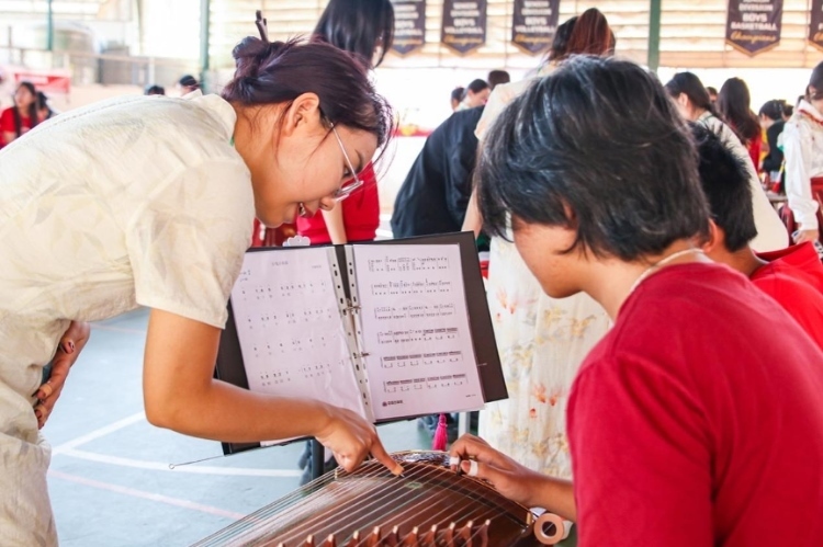 志愿者教師指導(dǎo)學(xué)生彈奏古箏。活動主辦方供圖