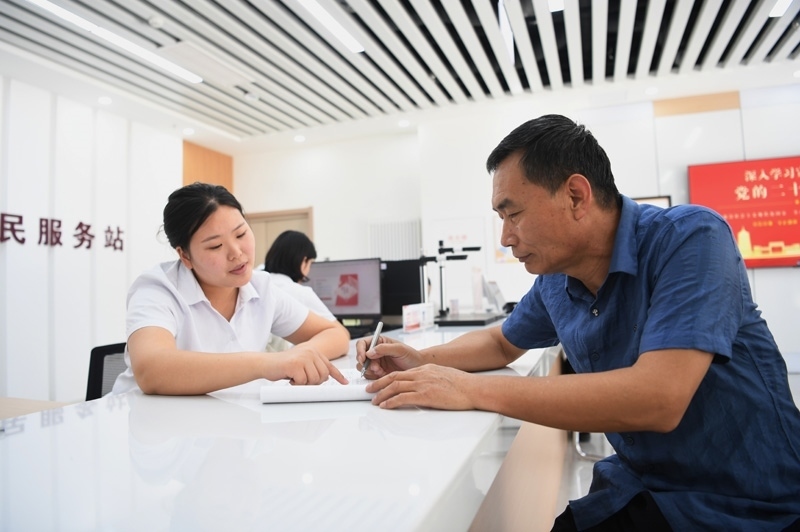 2023年5月23日，河北雄安新區(qū)容東片區(qū)南文營社區(qū)居民（右）在社區(qū)便民服務(wù)站辦理業(yè)務(wù)。