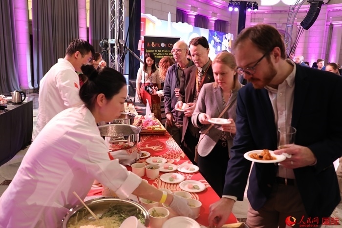 當?shù)貢r間3月7日晚，華盛頓聯(lián)合車站廣場舉行駐美使團“使館主廚挑戰(zhàn)賽”。圖為當?shù)孛癖娫谥袊古_前體驗中國美食。人民網(wǎng)記者 李志偉攝