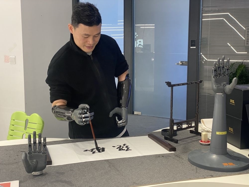 2024年3月29日，在浙江強(qiáng)腦科技有限公司展廳內(nèi)，失去雙手的產(chǎn)品體驗(yàn)官倪敏成依靠智能仿生手寫毛筆字。新華社記者 魏一駿 攝