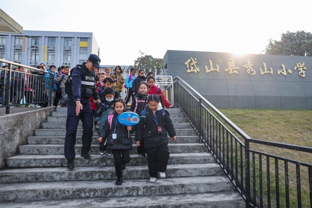 2023年12月20日，秀山派出所民警在秀山小學(xué)放學(xué)時(shí)間參與“護(hù)學(xué)崗”維持秩序，同時(shí)接獨(dú)自放學(xué)的學(xué)生去“民生小鋪”。浙江省舟山市岱山縣公安局秀山派出所聯(lián)合鄉(xiāng)鎮(zhèn)、社區(qū)成立“民生小鋪”，為當(dāng)?shù)鼐用?、外來?wù)工人員及其子女等服務(wù)，協(xié)助解決外來務(wù)工人員在工作、生活等方面的矛盾和問題，助力鄉(xiāng)鎮(zhèn)基層治理。新華社記者 徐昱 攝