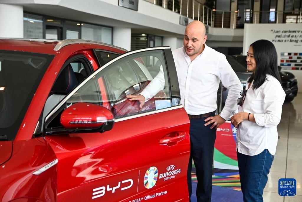 2024年5月29日，在馬耳他比爾基卡拉，馬耳他哈桑-扎米特汽車公司首席執(zhí)行官德古阿拉（左）介紹一輛比亞迪純電動汽車。新華社發(fā)（喬納森·博格 攝）