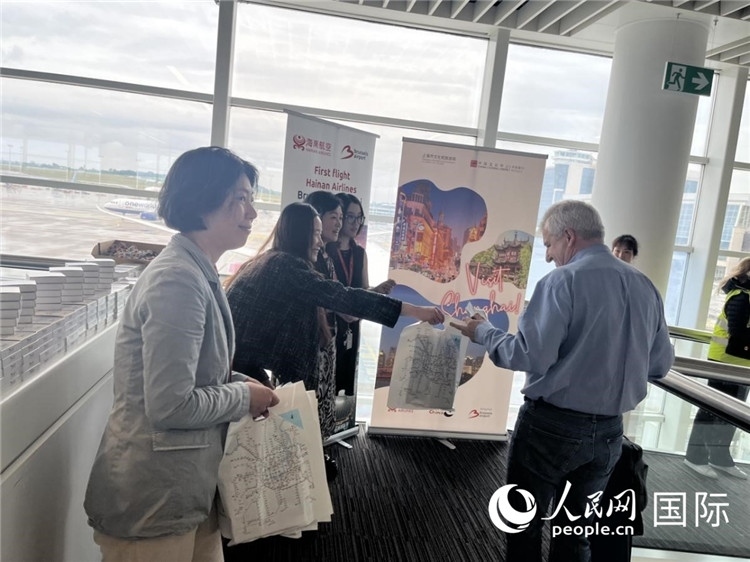 圖為工作人員向乘客發(fā)放復航首班禮物。 牛瑞飛攝