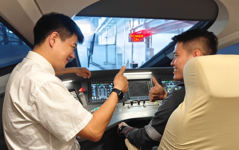 2023年8月25日，在印度尼西亞萬(wàn)隆的雅萬(wàn)高鐵德卡魯爾動(dòng)車(chē)所內(nèi)，中國(guó)師傅穆振（左）向印尼火車(chē)司機(jī)塞蒂亞萬(wàn)講解動(dòng)車(chē)組出庫(kù)前的上電作業(yè)。新華社記者 徐欽 攝