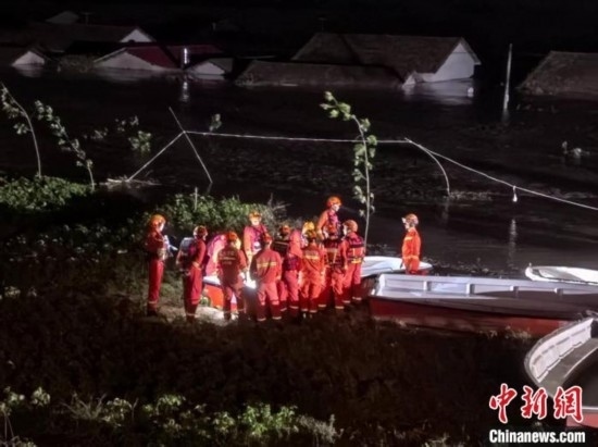  7月6日凌晨3時，在湖南岳陽華容縣團洲垸洞庭湖一線堤防，救援人員剛剛完成一次救援任務，遠處是被淹的民房。中新社記者 白祖偕 攝