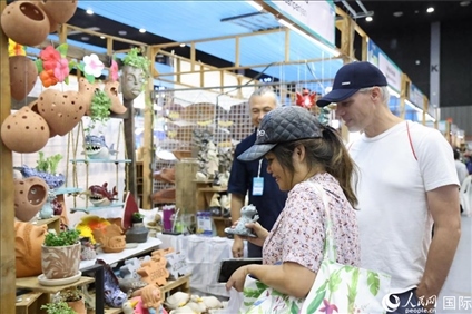 游客在蘭納博覽會特色展位上選購工藝品。人民網(wǎng)記者楊一攝