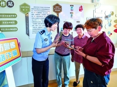 浙江湖州民警指導(dǎo)居民加入湖州“e企安”微信群，實時接收反詐信息。新華社發(fā)