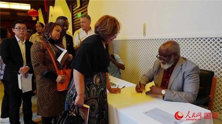 譚哲理在活動(dòng)現(xiàn)場(chǎng)簽名贈(zèng)書。人民網(wǎng) 劉暢攝