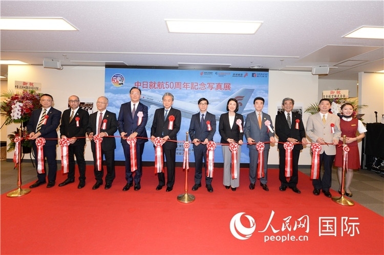 與會(huì)嘉賓共同為中日通航50周年紀(jì)念圖片展開幕剪彩。馮學(xué)敏攝
