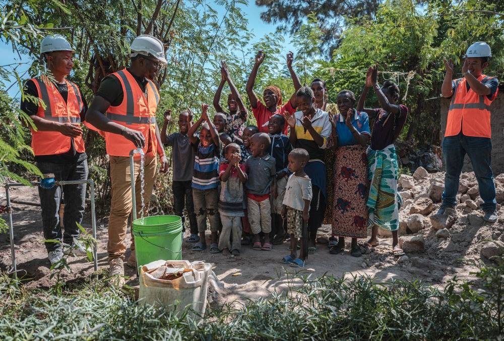 2023年6月13日，在坦桑尼亞姆萬(wàn)扎省米松圭，工作人員接通水管后贏得當(dāng)?shù)鼐用窆恼茪g呼。新華社記者 王冠森 攝