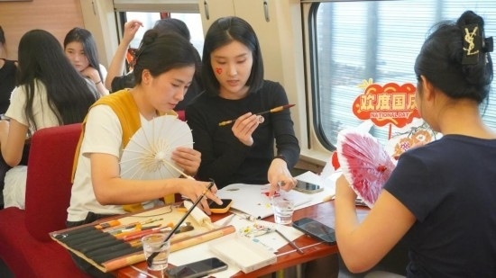 10月1日，旅客們在G1634次列車上給油紙傘作畫。新華社記者周義 攝