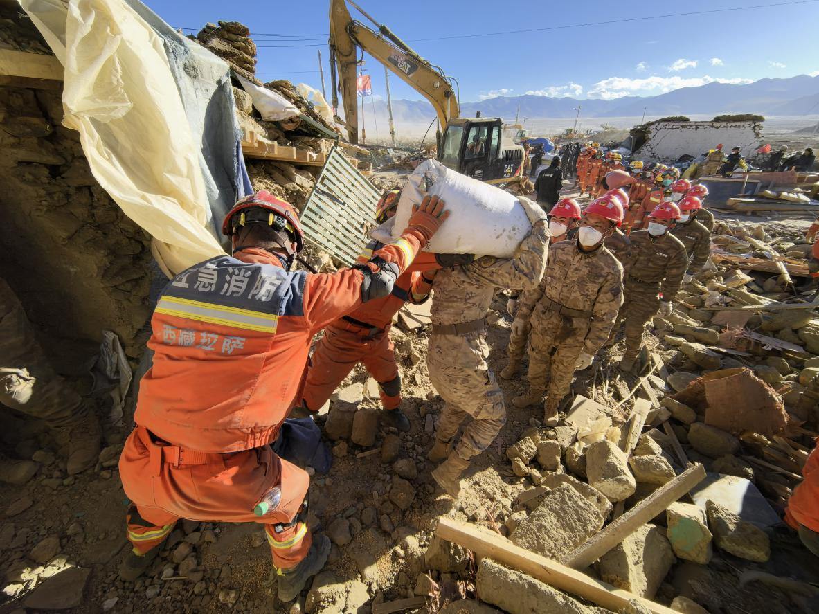 1月11日，定日縣長(zhǎng)所鄉(xiāng)古榮村，應(yīng)急消防等救援人員排隊(duì)接力搶運(yùn)掩埋在倒塌房屋下的群眾財(cái)物。人民日?qǐng)?bào)記者楊翹楚攝