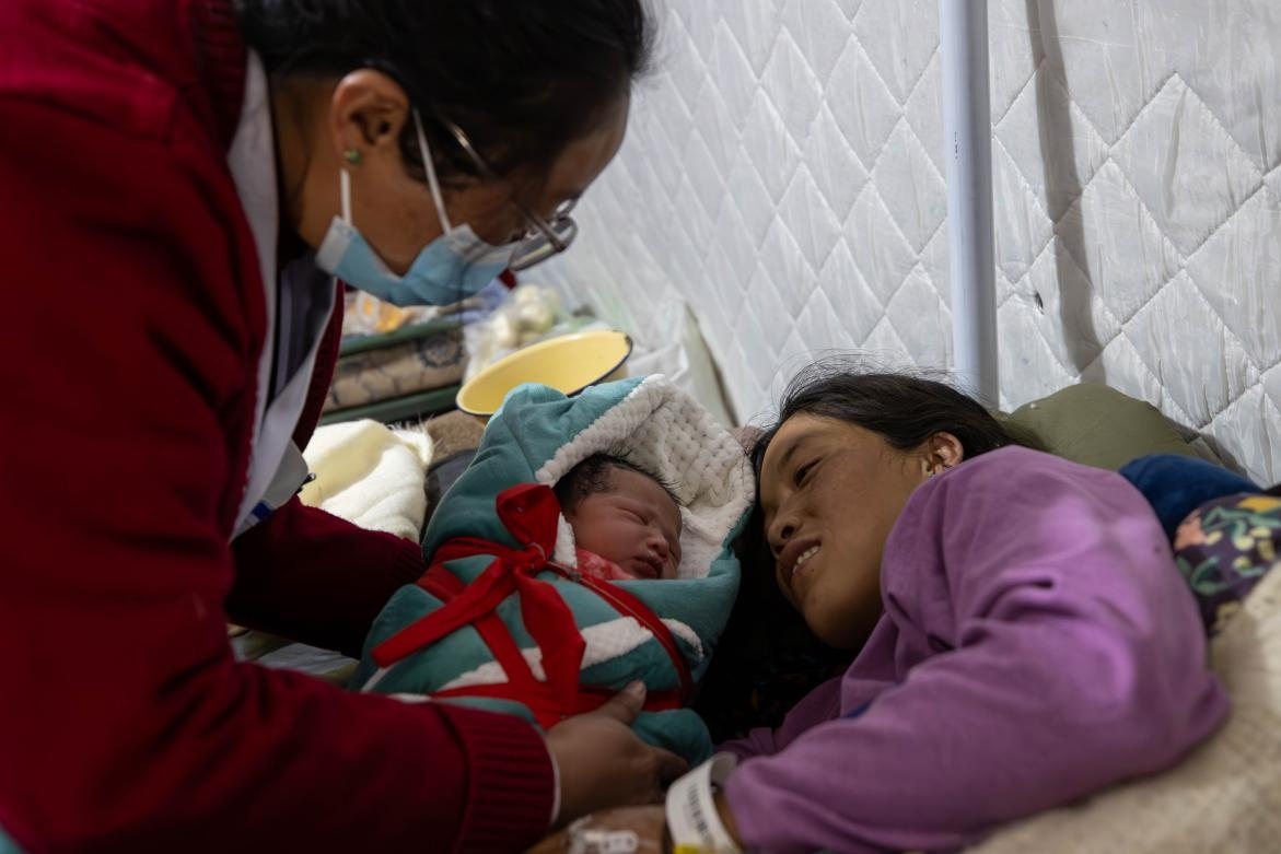 1月10日，定日縣中心醫(yī)院的婦產(chǎn)科醫(yī)生悉心照看一位母親和她懷里的新生兒。人民日?qǐng)?bào)記者張武軍攝