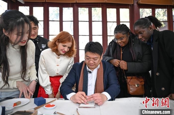 1月20日，篆刻家王臻向外籍留學(xué)生展示篆刻印章。當(dāng)日，來自巴西、馬來西亞、加納、哈薩克斯坦的外籍留學(xué)生在浙江杭州西泠印社體驗福貼、春聯(lián)和篆刻，感受古老的中國傳統(tǒng)文化。中新社記者 王剛 攝
