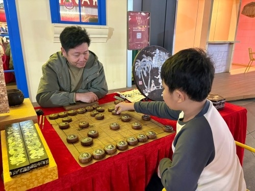 柯秋楓與市民下椰雕象棋。人民網(wǎng) 陳葉欣攝