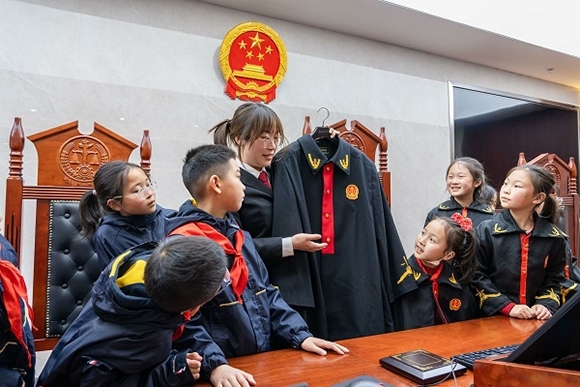 圖②：干警向同學(xué)們介紹法袍。