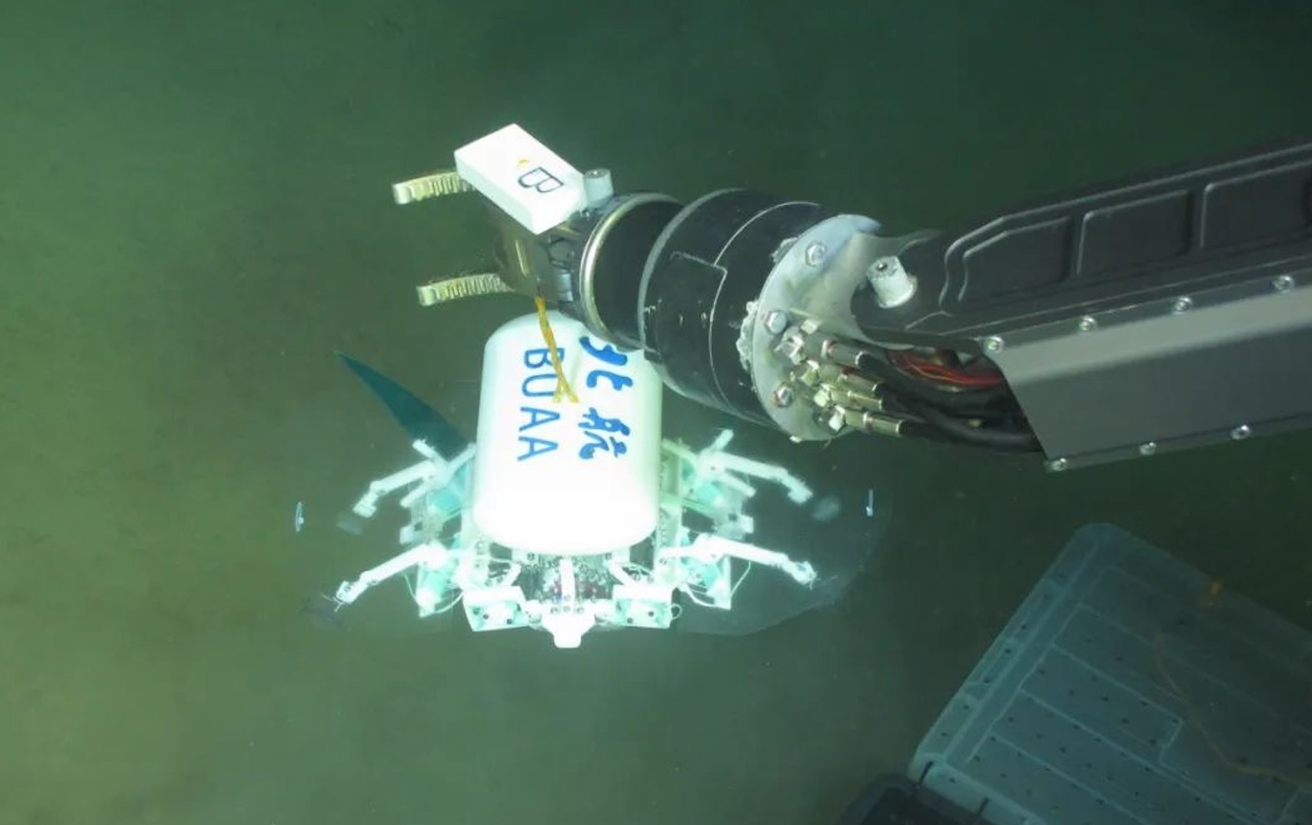 科研人員利用機(jī)械臂將北航深海小型機(jī)器人投于馬里亞納海溝。校方供圖