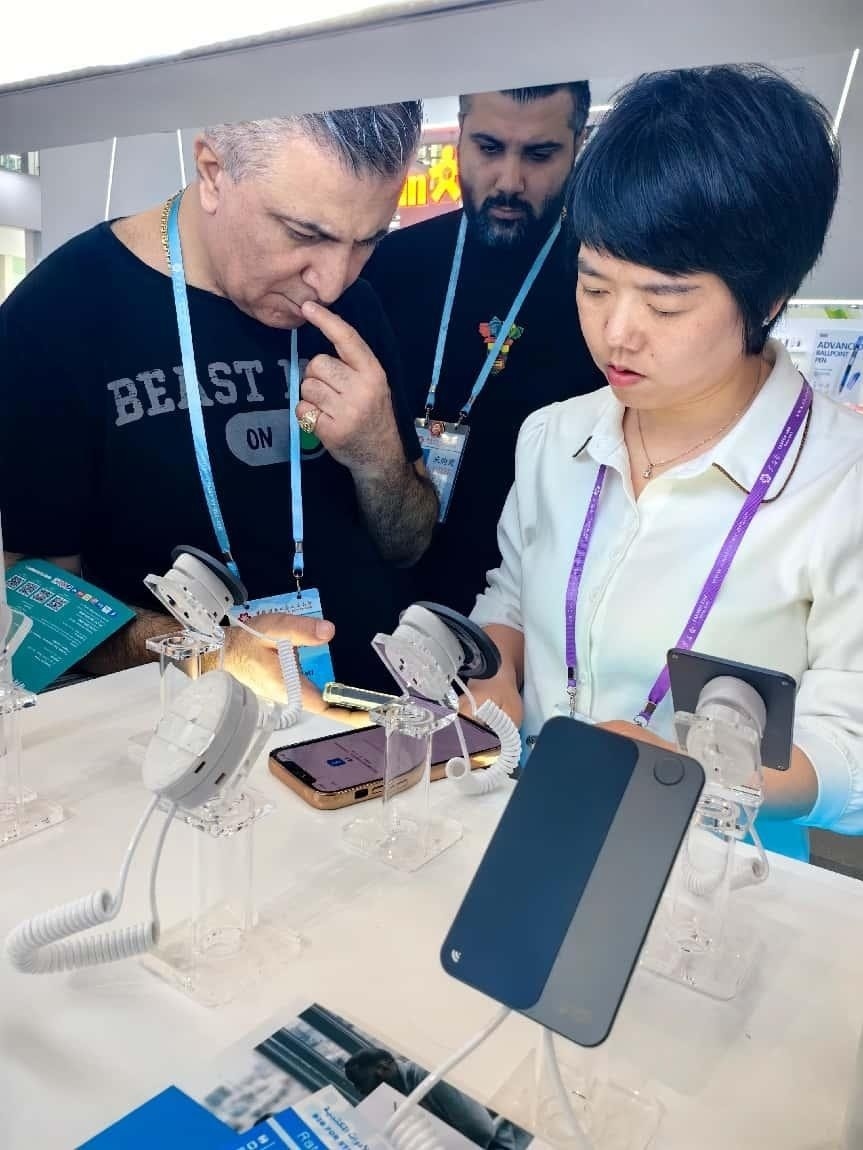 展臺(tái)工作人員向外商展示“AI TOP翻譯終端”。圖片來源：受訪者提供