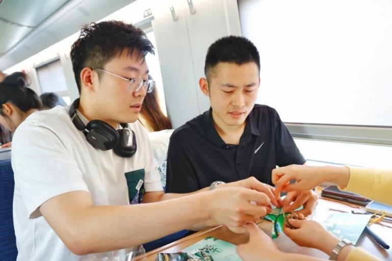 G232次旅客親手制作端午荷包和五彩繩。王磊攝