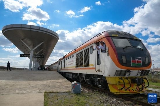 5月31日，在蒙內(nèi)鐵路內(nèi)羅畢站，機車駕駛員蔣立平（右）和博爾在即將開往蒙巴薩的E2次列車上揮手致意。新華社記者 楊光 攝