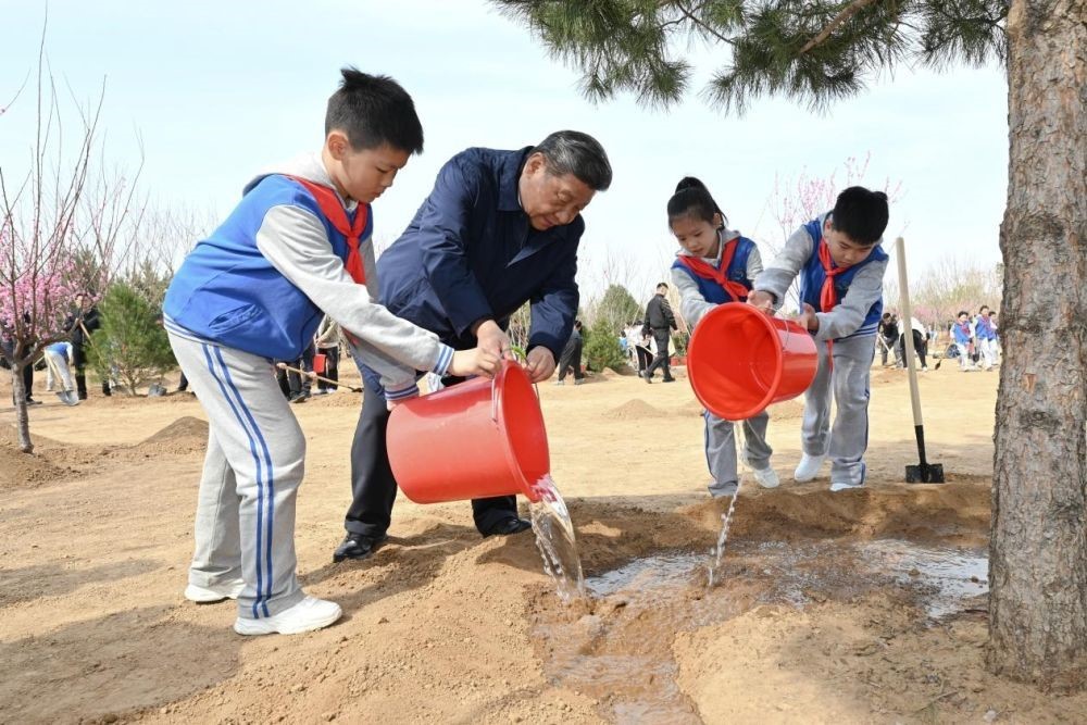 2025年4月3日，習(xí)近平總書記等來到北京市豐臺區(qū)永定河畔參加首都義務(wù)植樹活動。這是習(xí)近平總書記同少先隊(duì)員一起給剛栽下的樹苗澆水。新華社記者 謝環(huán)馳 攝